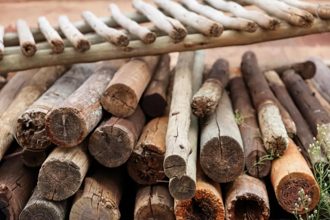A stack of debarked natural wooden poles cut to length